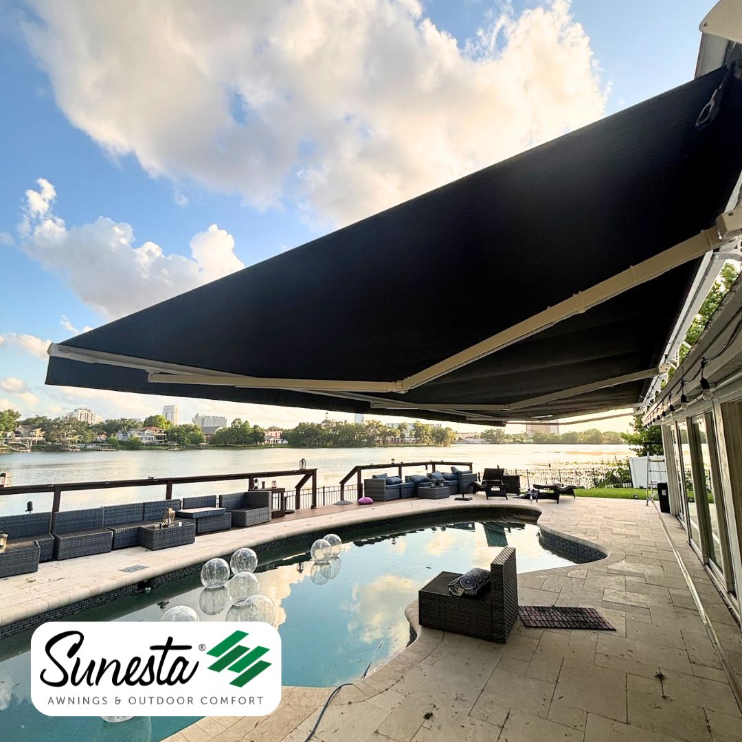 A wide Sunesta retractable awning shading a lakeside pool patio