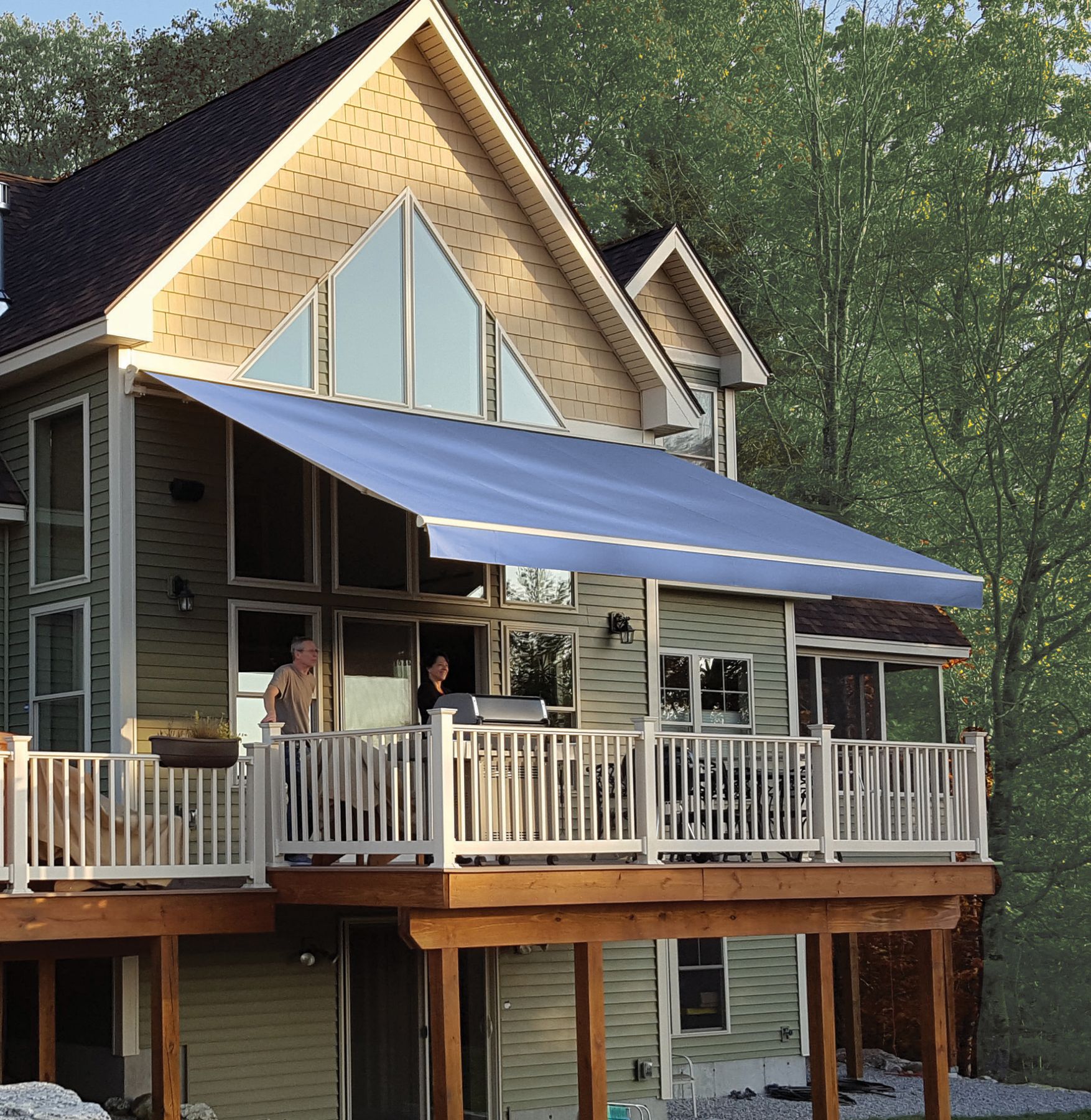 A blue-striped Sunesta retractable awning shading a second-story deck