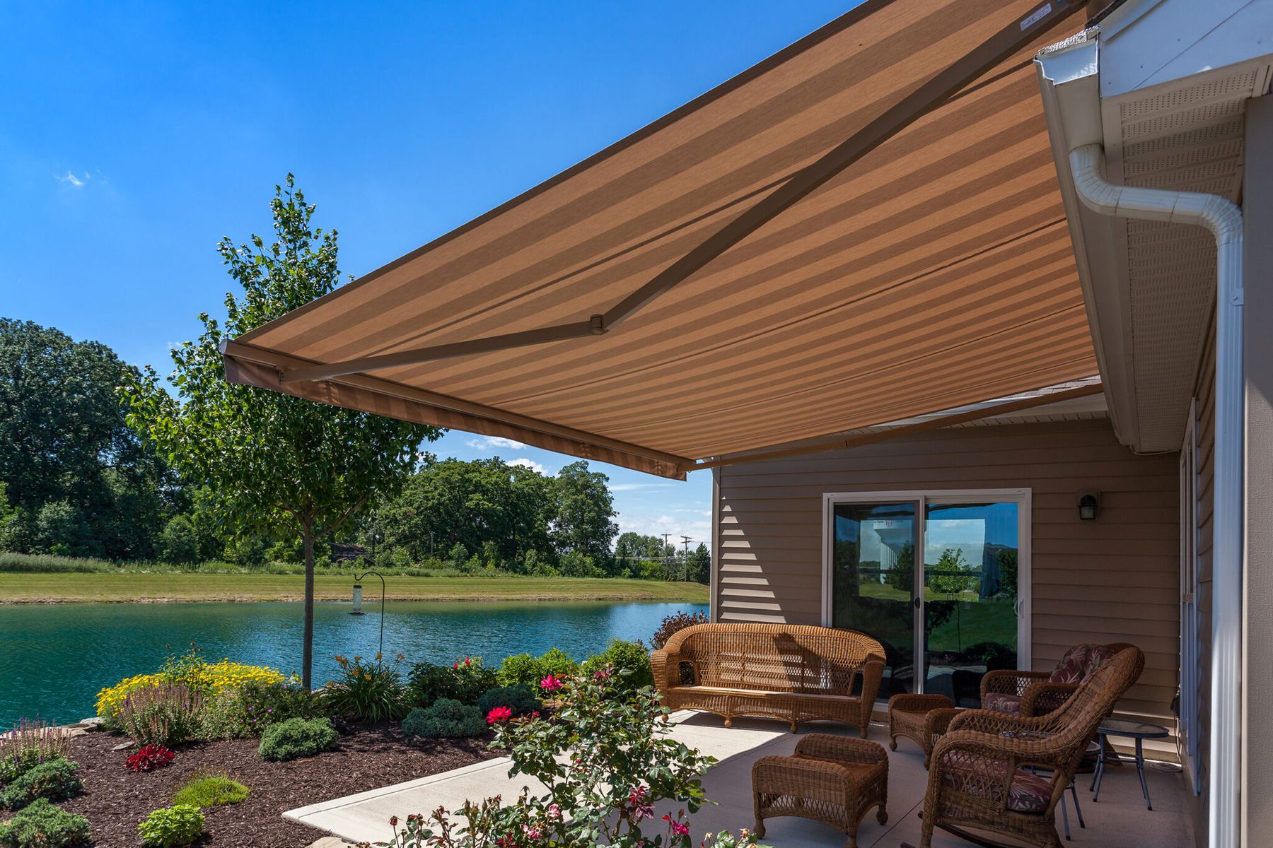 A tan Sunesta awning shading a lakeside patio seating area