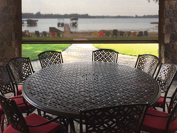 A retractable screen shading a covered porch with wicker furniture