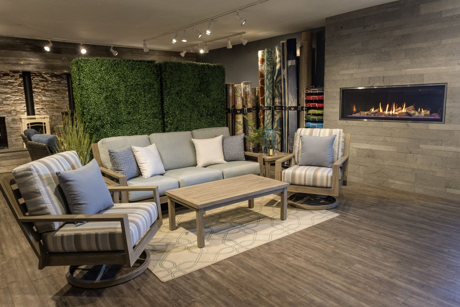 A teak-look sofa and swivel chairs in front of a linear gas fireplace on the showroom floor