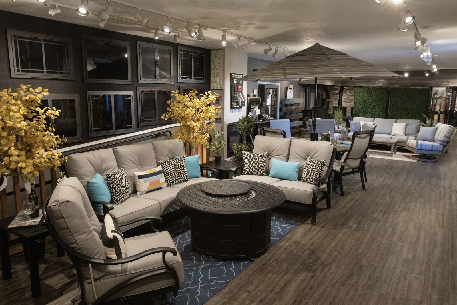 A deep-seating conversation set around a fire table on the showroom floor, with a wall of fireplace fronts behind it