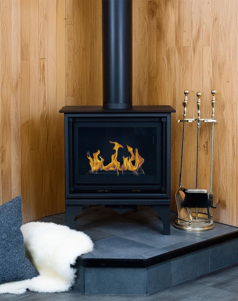 A small wood stove on a black tile corner hearth pad