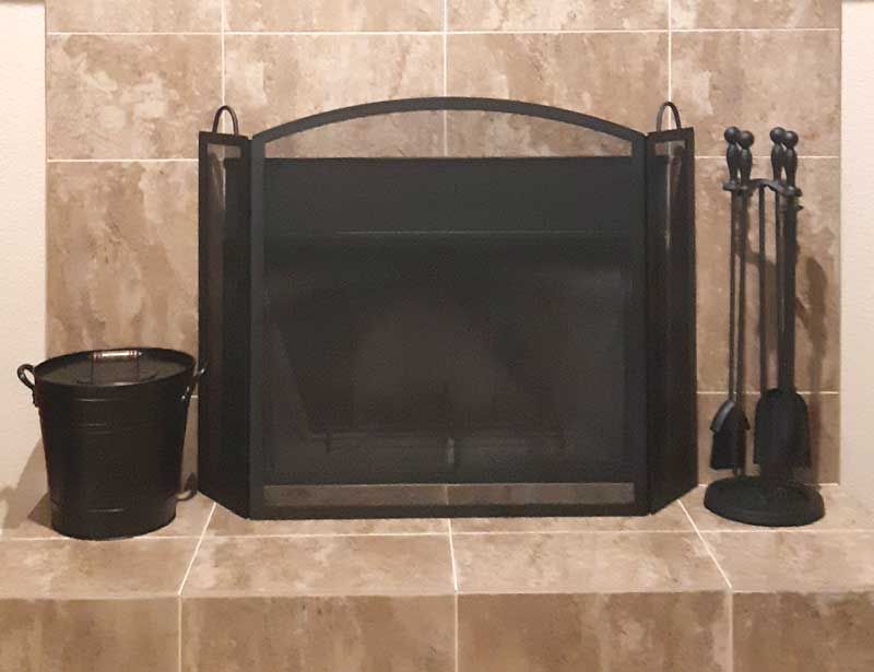 Pilgrim full-arch fireplace screen with a matching tool set and ash bucket on a stone hearth