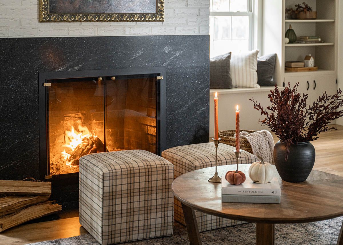 A lit masonry fireplace fitted with black Stoll glass doors in a cozy living room