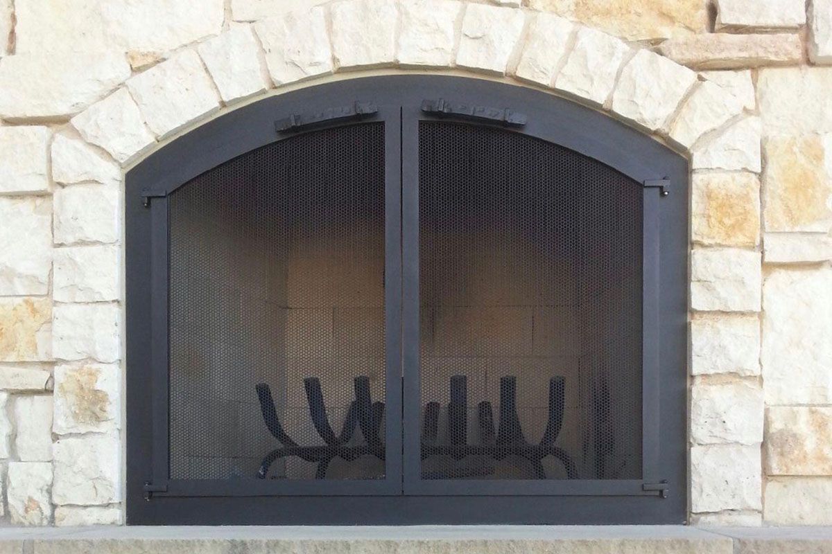 Arched Stoll glass doors on a stone arch fireplace
