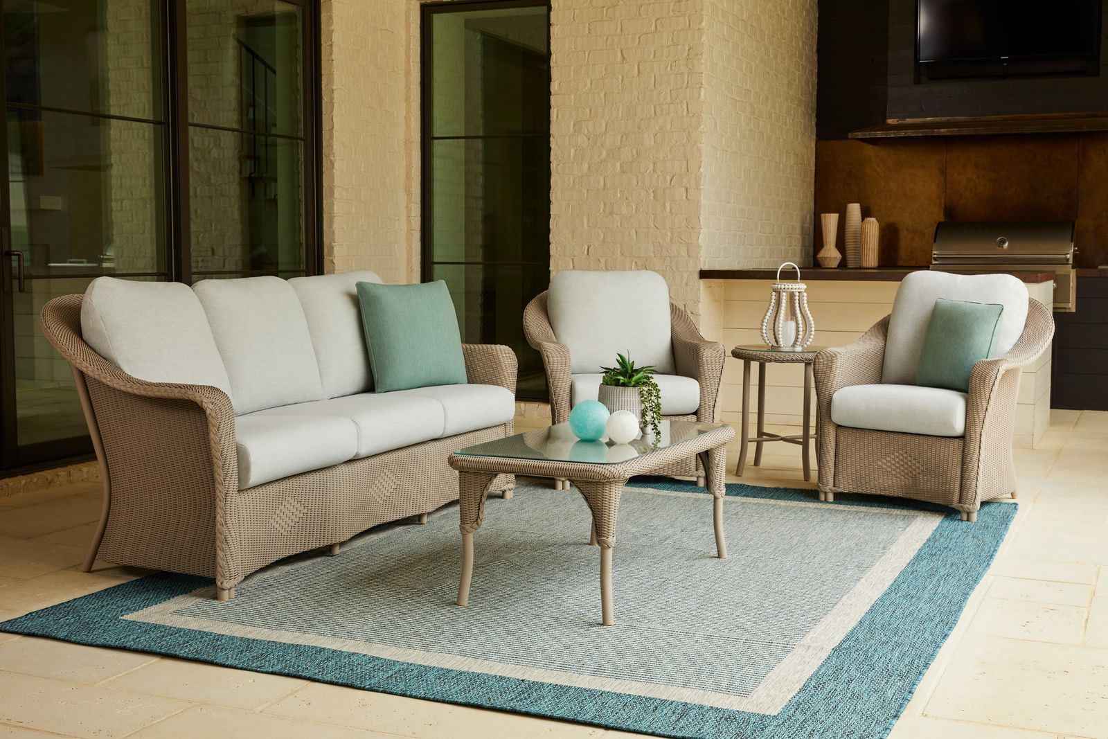 The Lloyd Flanders Reflections sofa and chairs in French Beige Lloyd Loom on a covered stone porch
