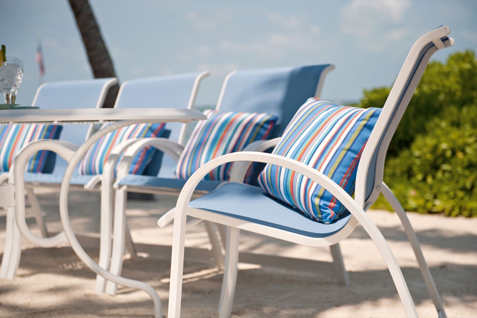 Close-up of white aluminum sling chairs with blue striped mesh seats